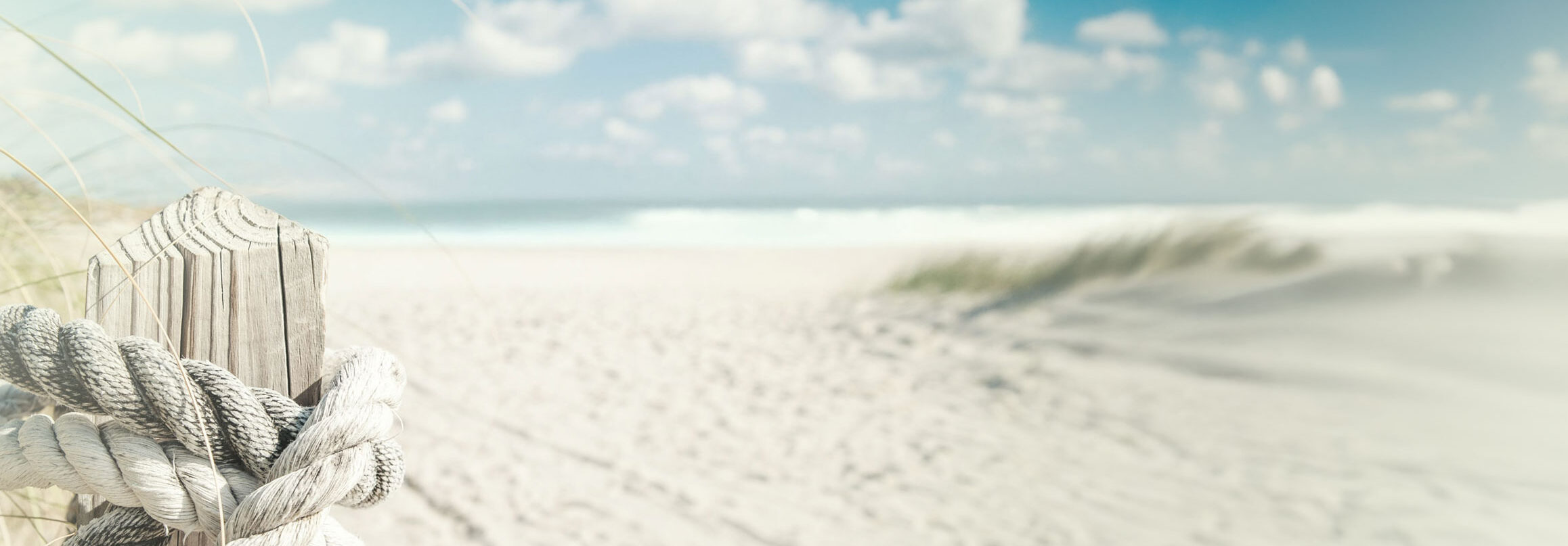 Ein großer menschenleerer Sandstrand, rechts kann man noch ein paar Dünen sehen, weiter im Hintergrund sieht man das Meer